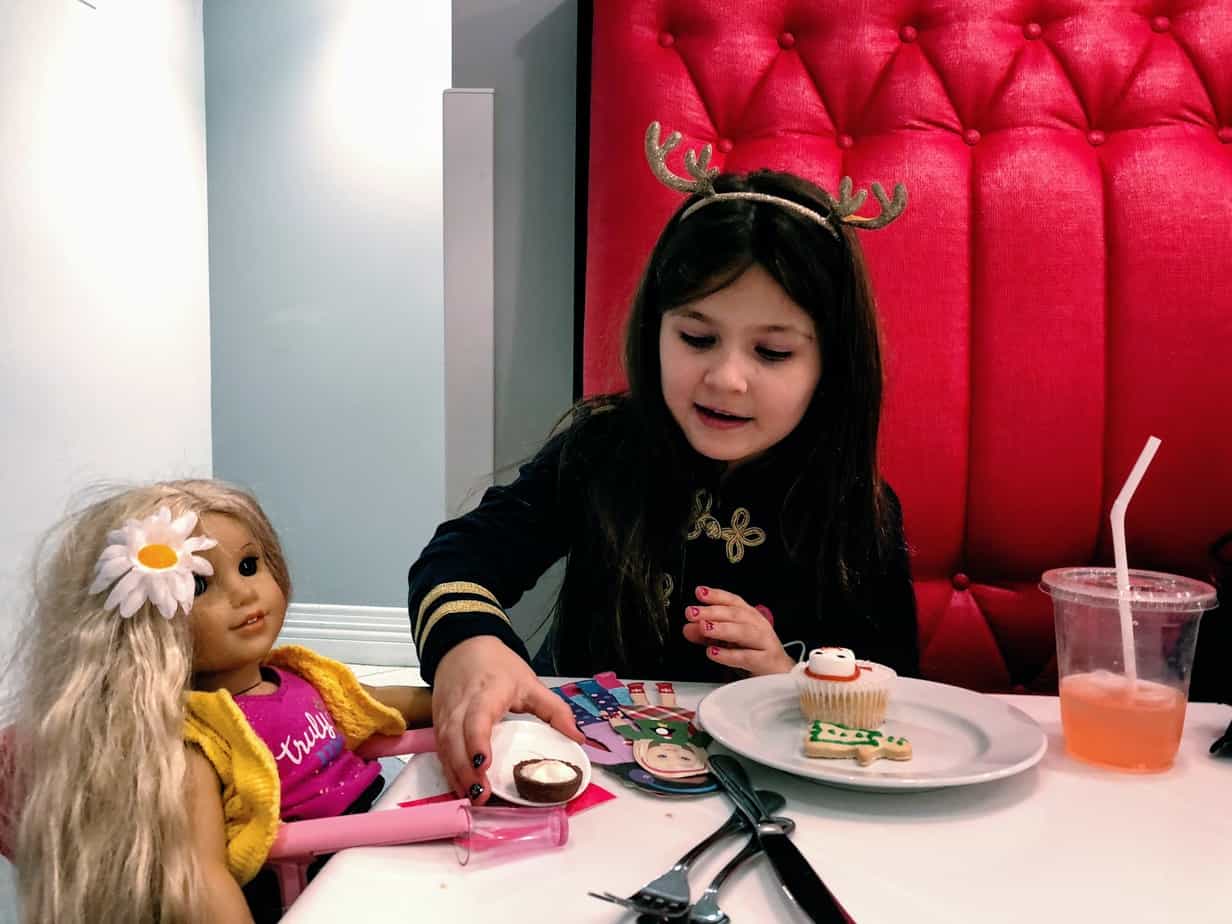 Daughter playing with American Girl doll at the American Girl doll cafe in NYC with Christmas cupcakes