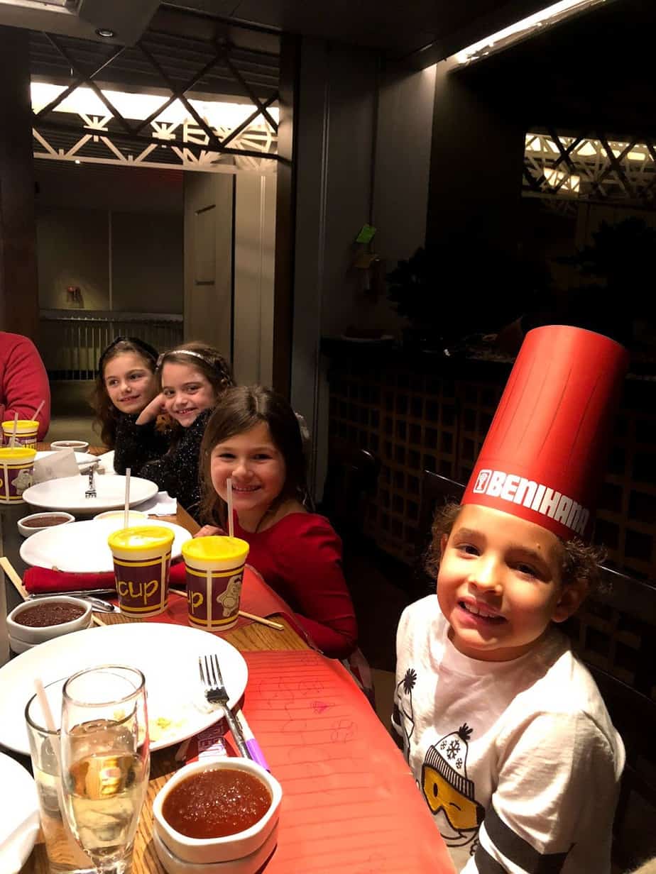 Kids sitting around table at Benihana wearing chefs' hats