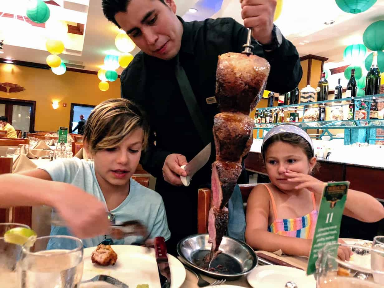 Fogo de Chao waiter serving meat to kids at the table