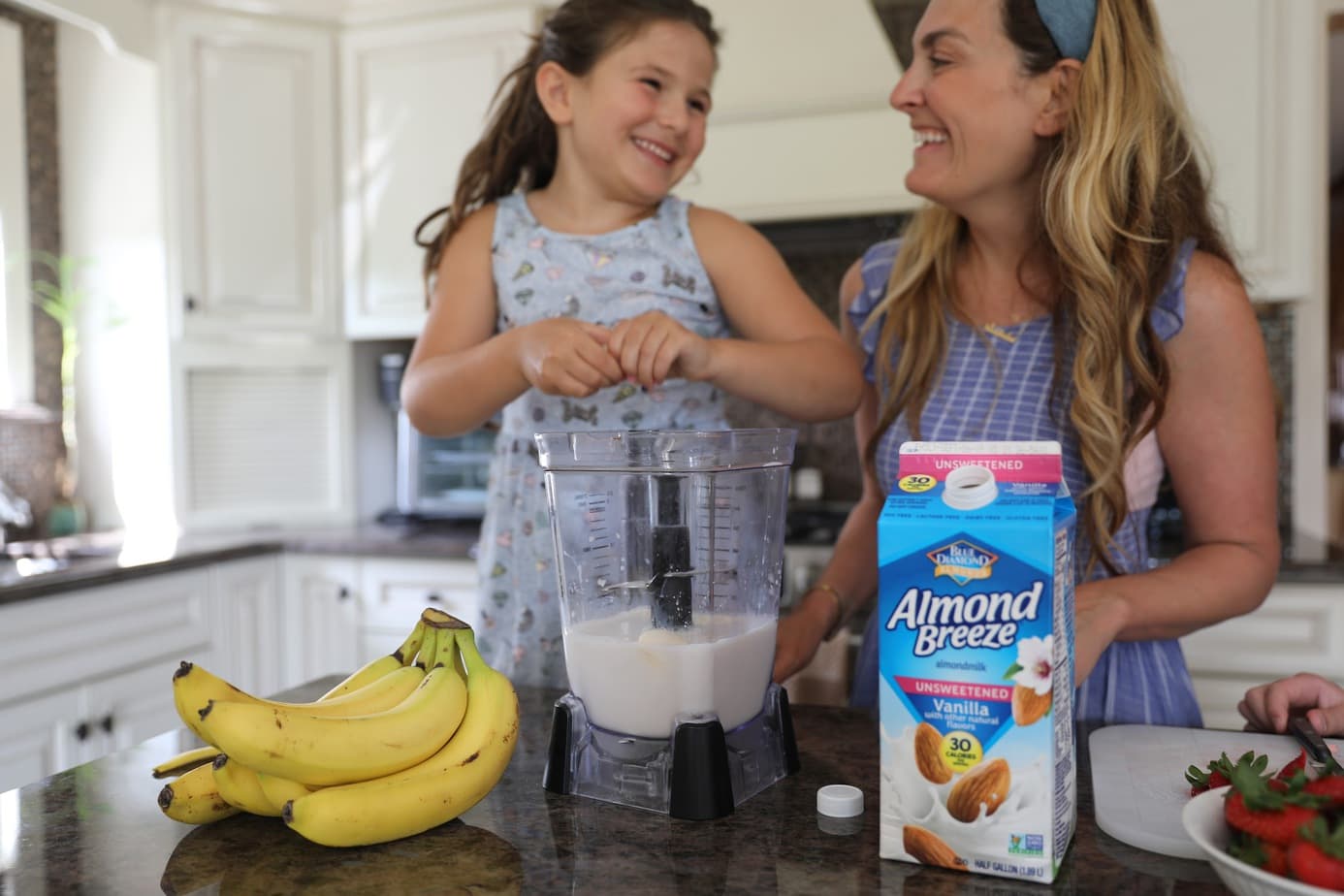 child adding ingredients to blender to make smoothie with best plant-based milk
