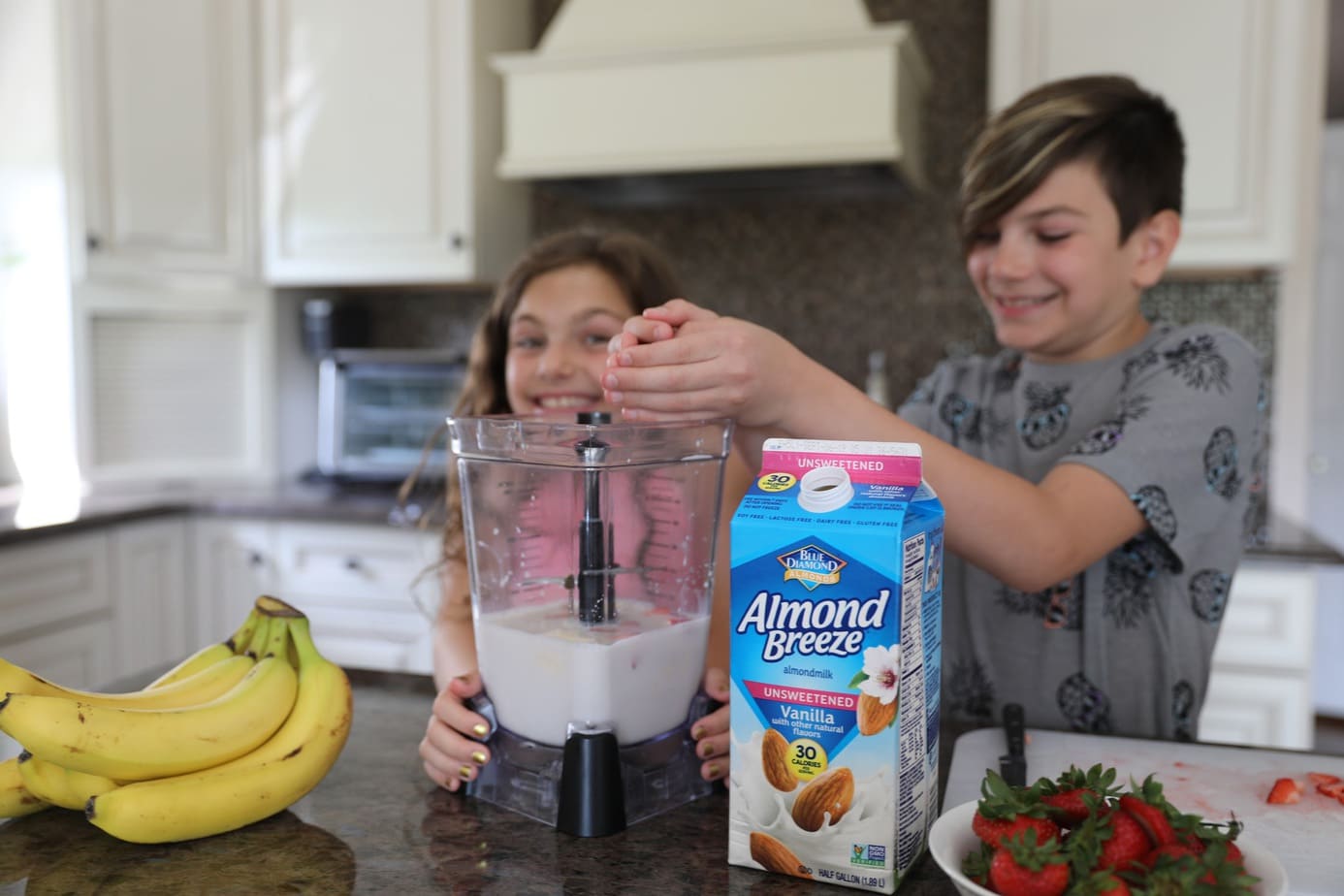 boy adding fruit to blender to make smoothie with best plant-based milk