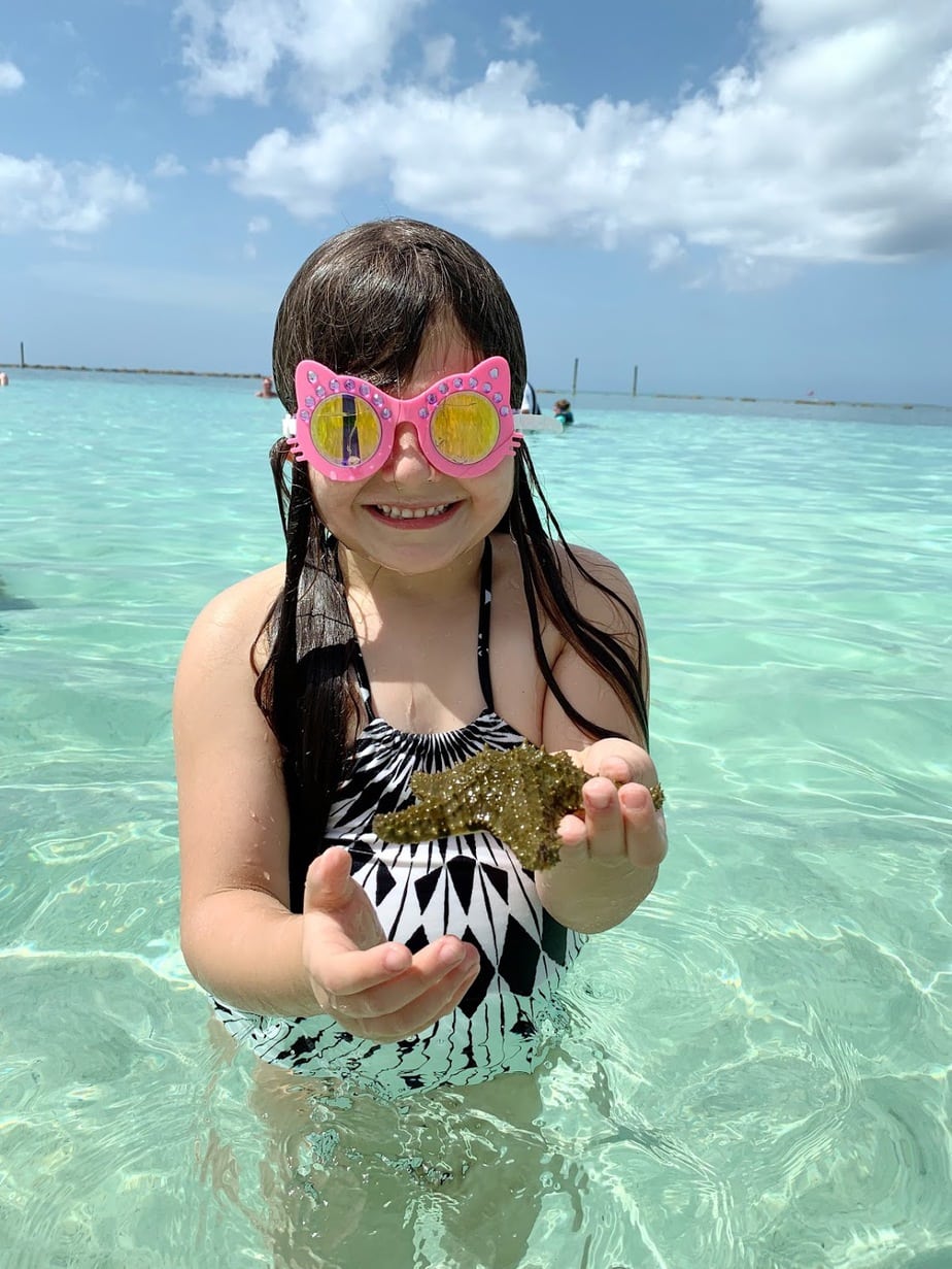 Girl with starfish in the waters at Baha Mar in the Bahamas