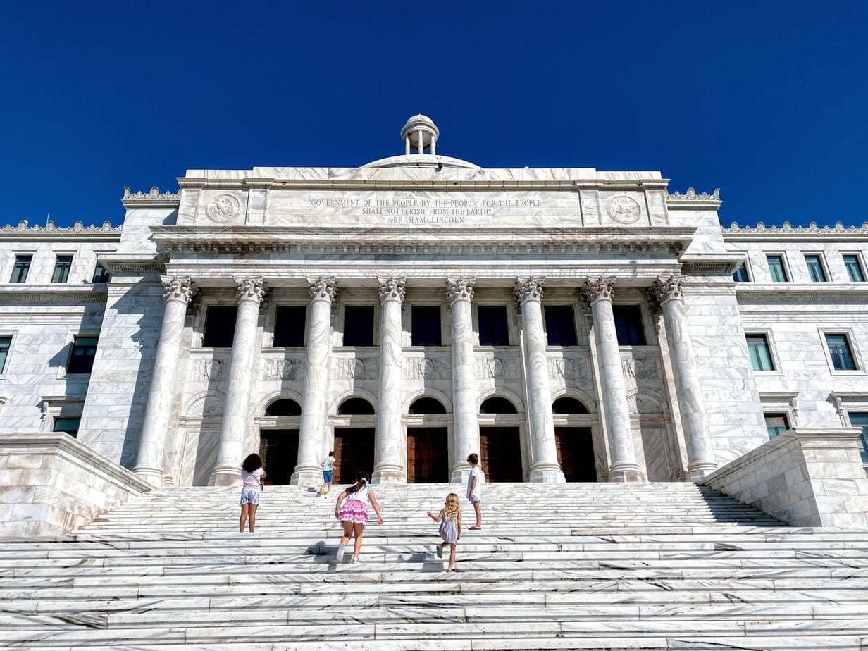 Children running up the steps of the traditional style government building in San Juan