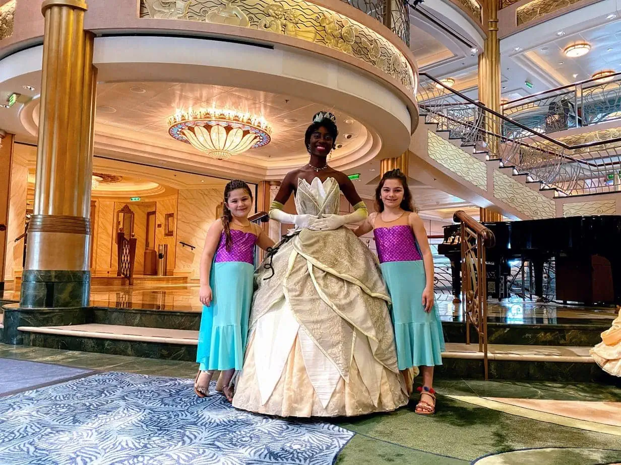 Daughters in matching mermaid outfits posing with Disney character Princess Tiana from the movie "Princess in the Frog"