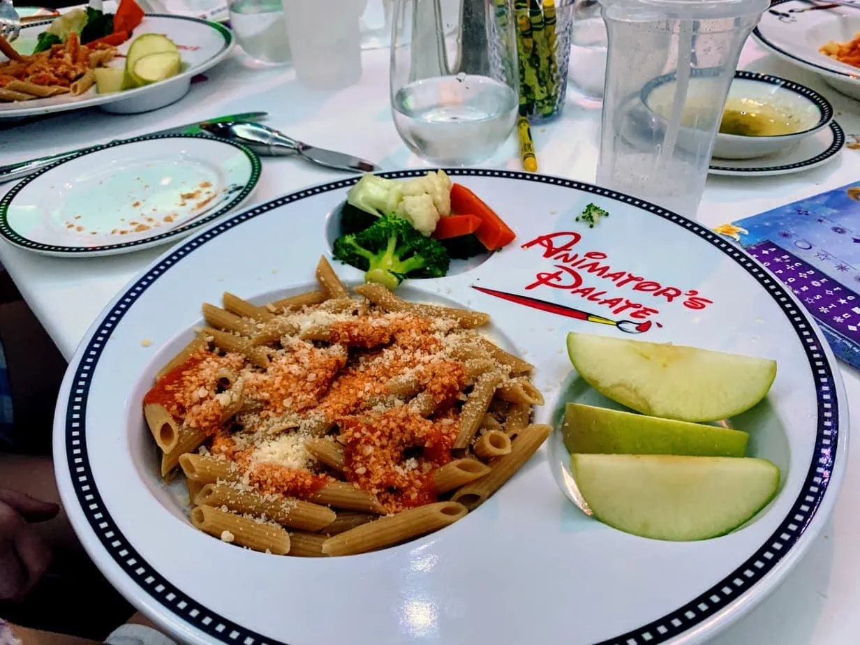 Dinner of pasta, green apples, and vegetables on Disney Cruise Animator's Palette Mickey Mouse-shaped plate