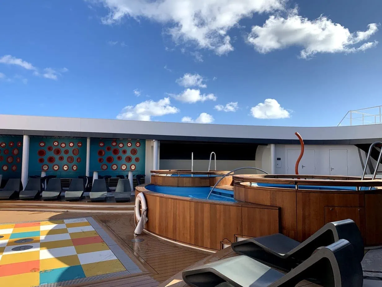 Disney cruise upper deck with pool and colorful tiled floors and blue skies
