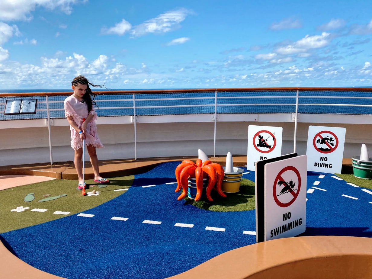 Daughter in all-pink ensemble playing mini golf on the Disney cruise deck