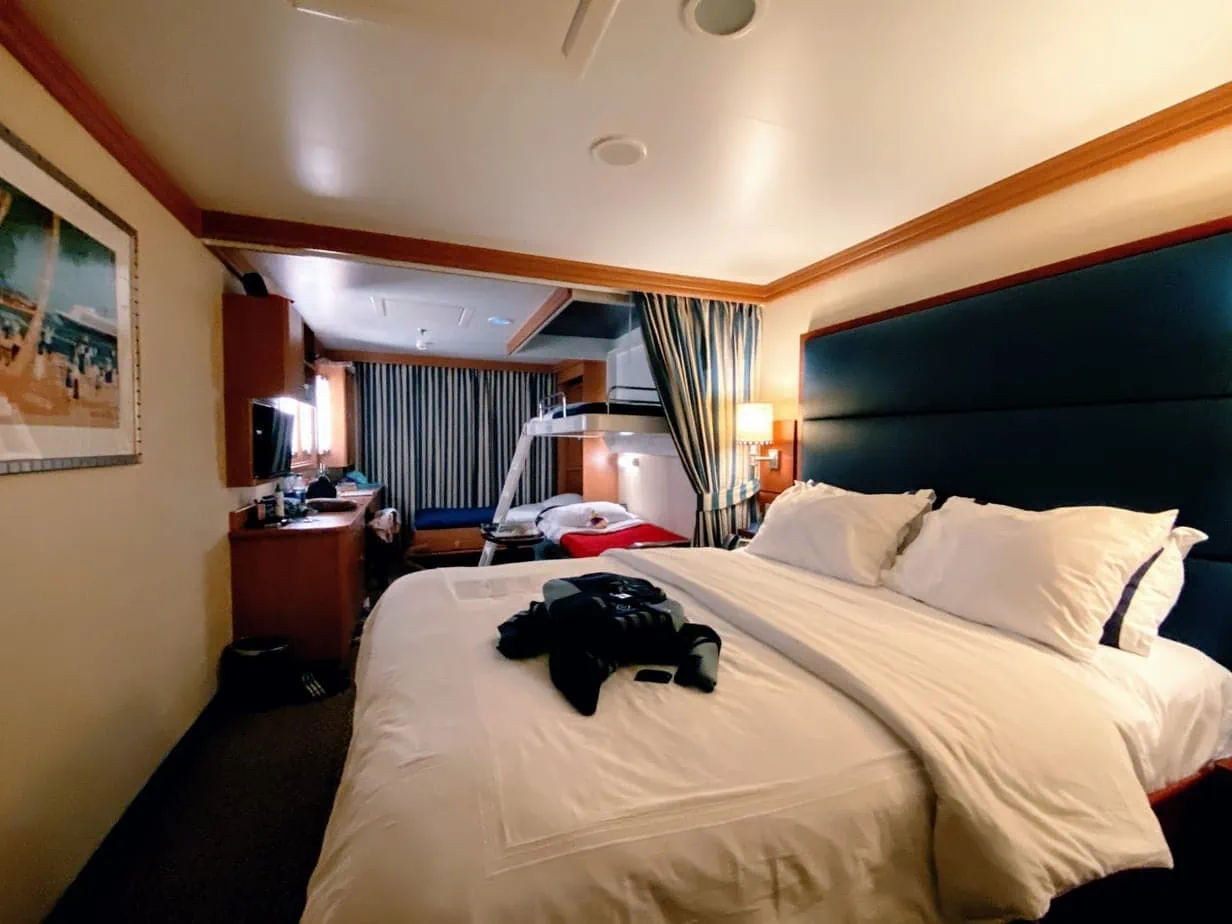 Disney cruise suite with white sheets on a queen bed 