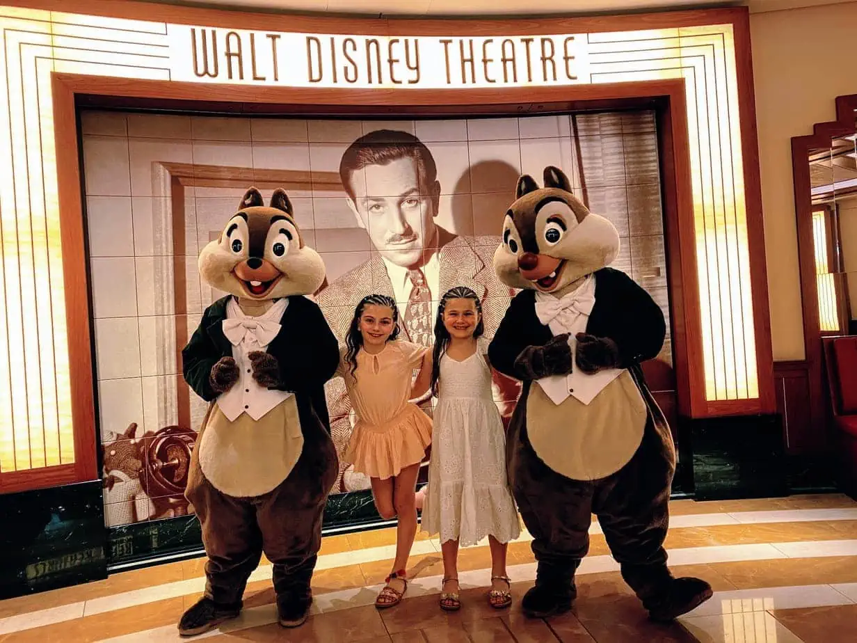 Daughters posing with Disney mascots "Chip and Dale" in front of Disney Cruise's "Walt Disney Theatre" sign