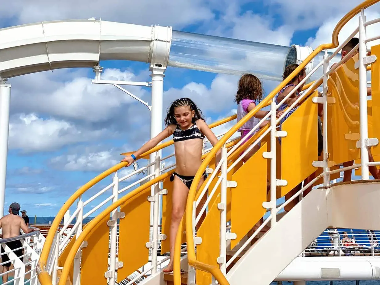 Kids running down yellow stairs of Disney cruise waterslide