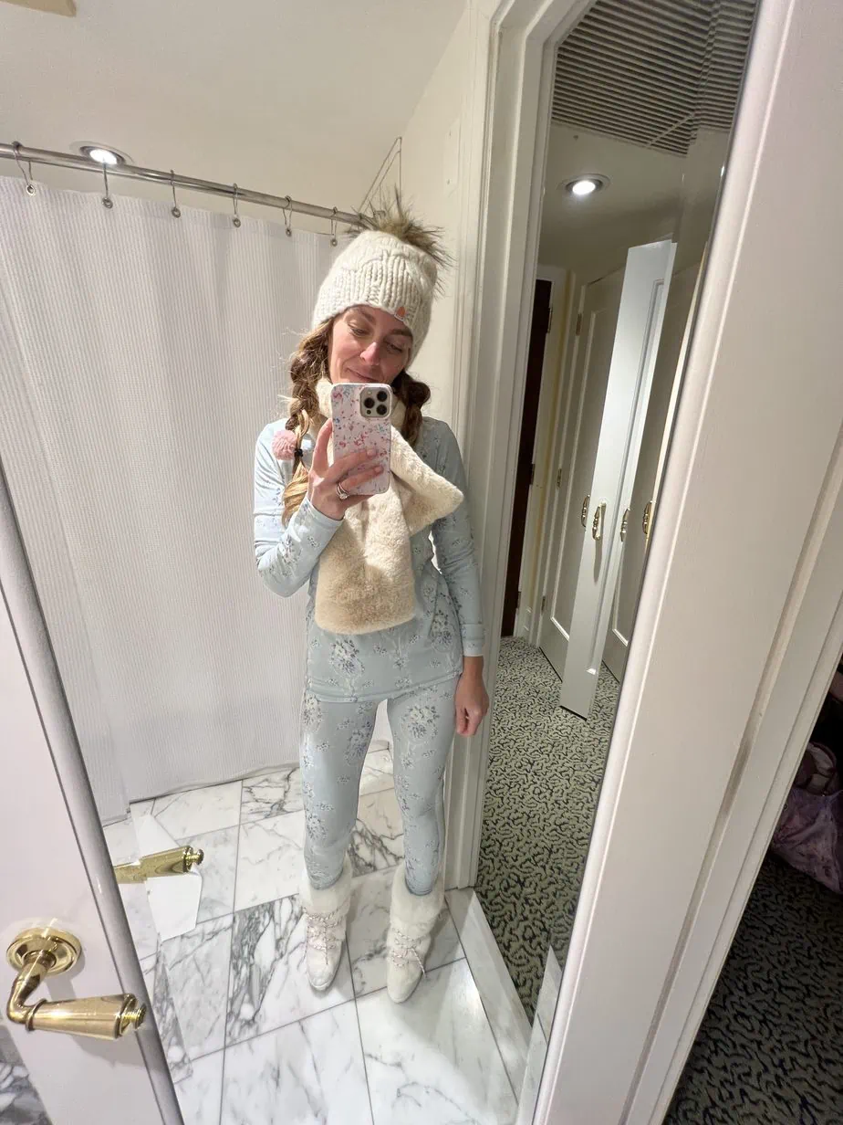 Mirror selfie of ski outfit with white hat, scarf, and blue matching set