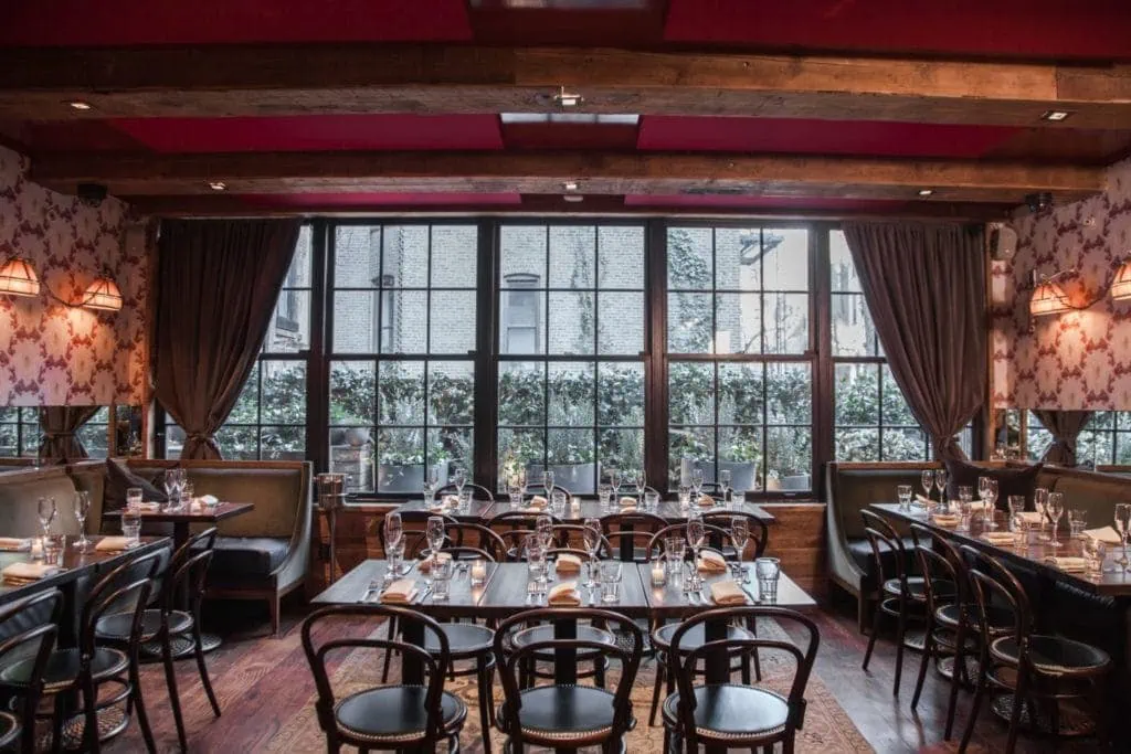 Best NYC fall restaurant Leroy House's beautiful interior with wooden tables and expansive windows 