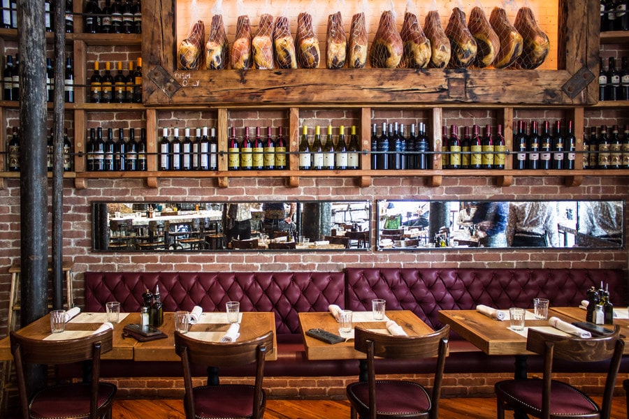 NYC best fall restaurants Terra wine bar's rustic interior with wooden tables and burgundy, velvet booth cushions