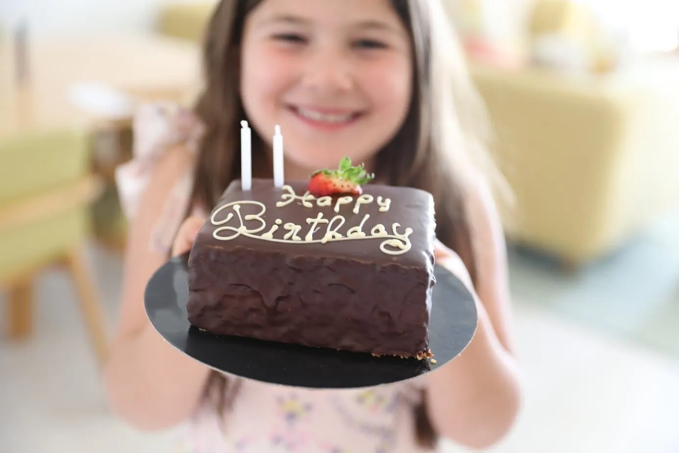 Daughter holding up piece of chocolate birthday cake