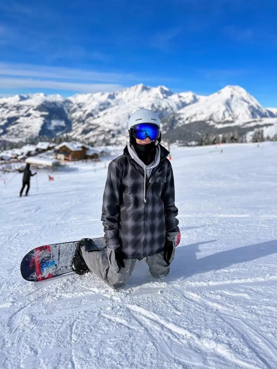 Son taking break while snowboarding on French alp mountain 