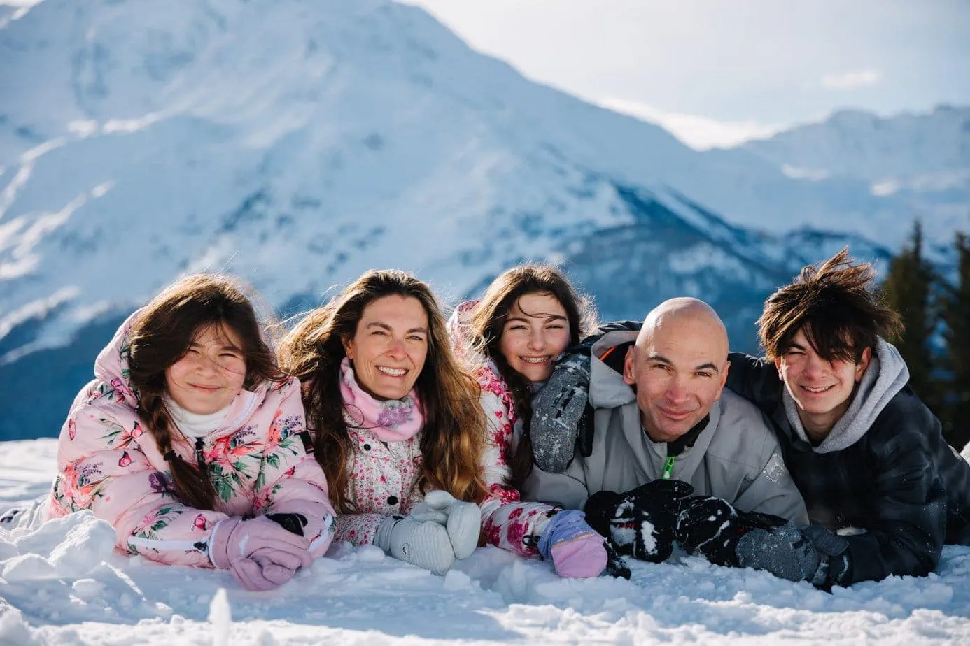 Cute family pose on French alps ski strip with snowy mountains background