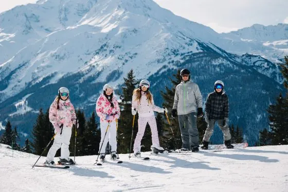 Family in cute outfits skiing in the scenic French Alps