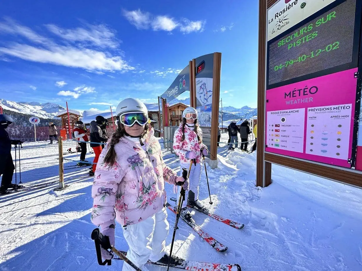 Daughters skiing in matching pink jackets and white snow pants 