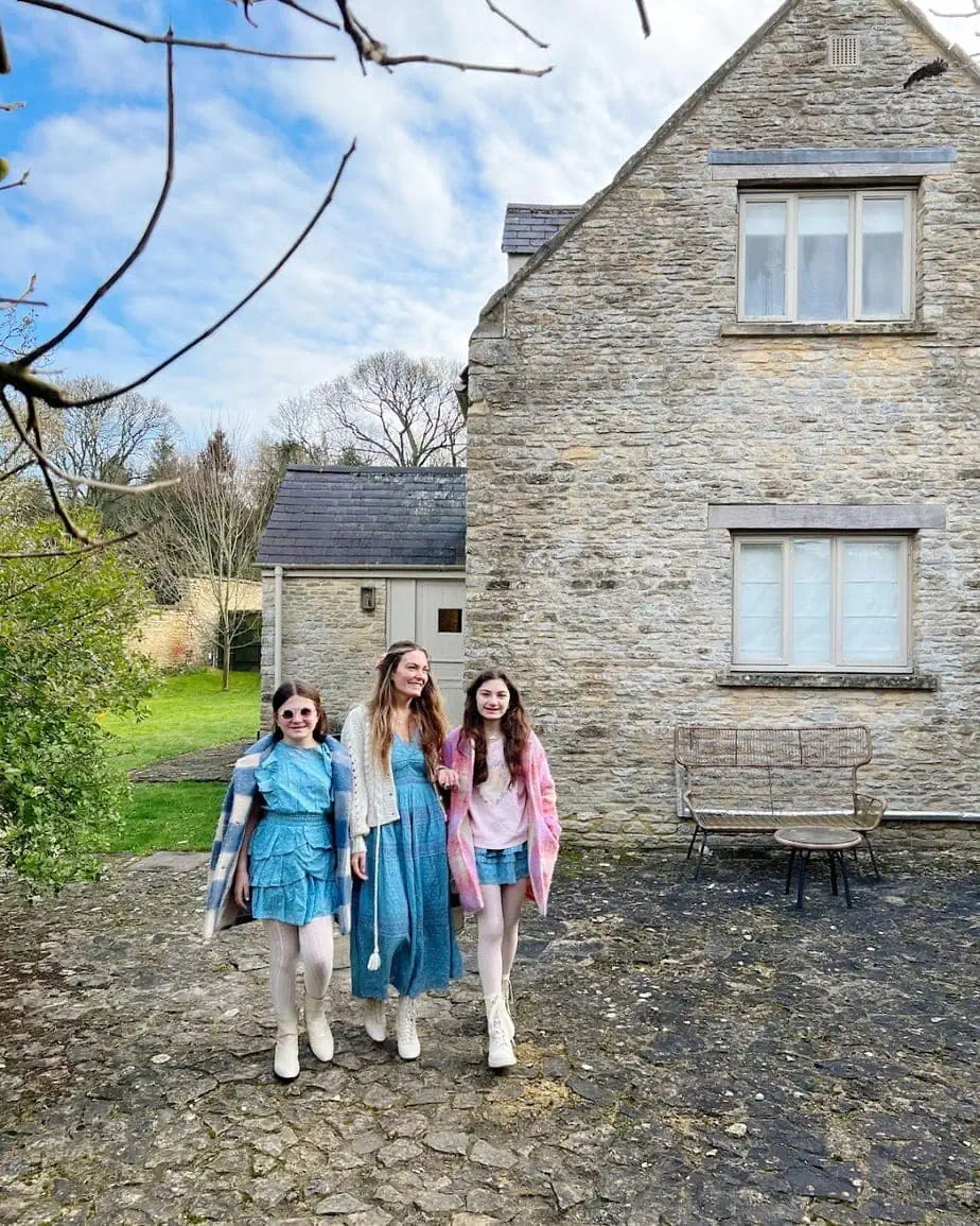 Mother and her daughters in cute outfits walking around the stone villages in Cotswolds