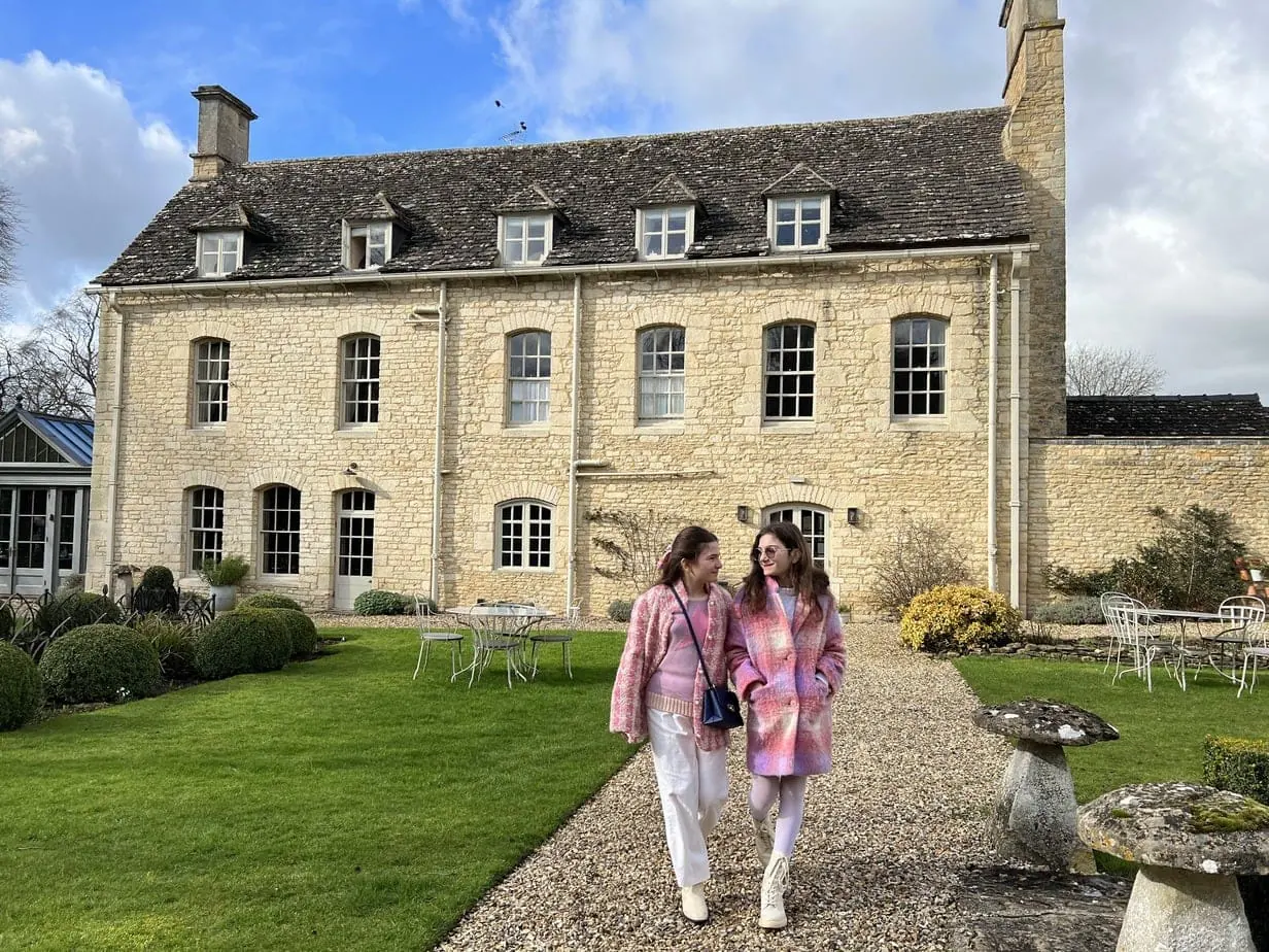 Daughters walking through garden of countryside English hotel