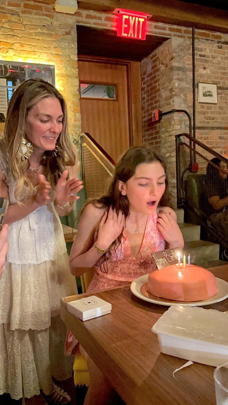 Daughter blowing out candles on pink birthday cake