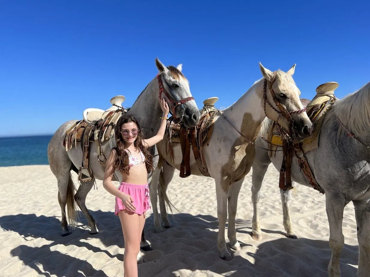 Daughter horseback riding on beach in Cabo