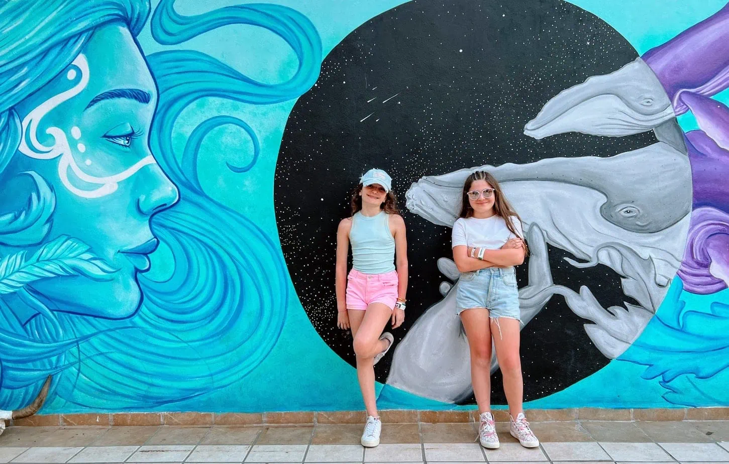Daughters posing with wall art mural in Mexico 