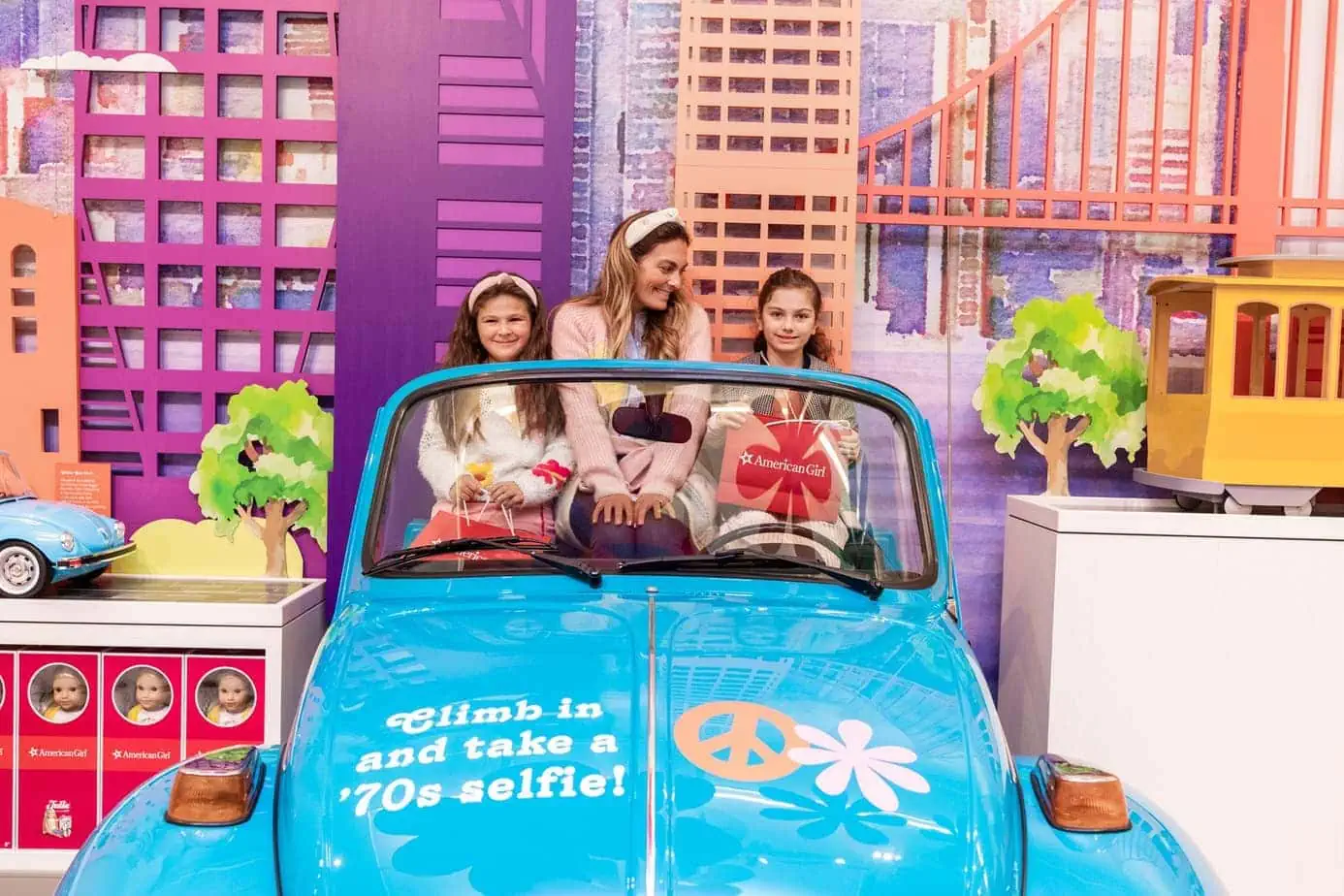Mother and Daughters at the American Girl Doll store posing in fake Buggie Car 