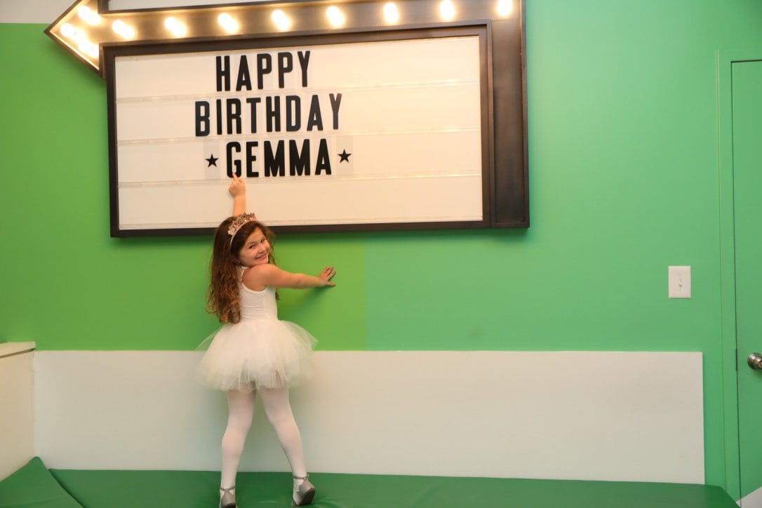 Daughter (Gemma) posing with a sign Text:/ Happy Birthday Gemma