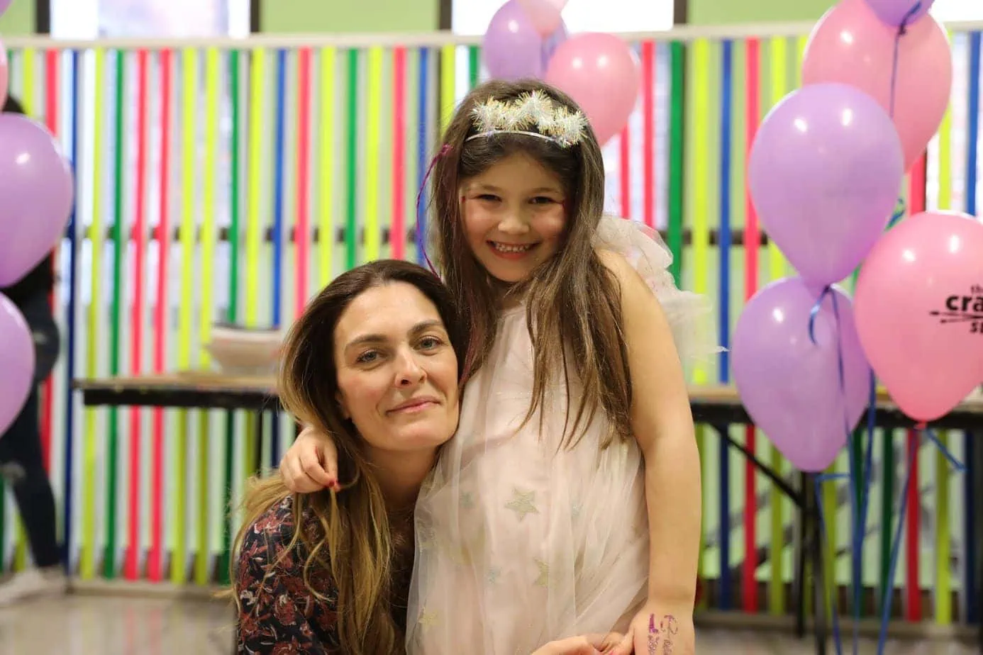 Mom and daughter hugging at a pink decorated birthday party