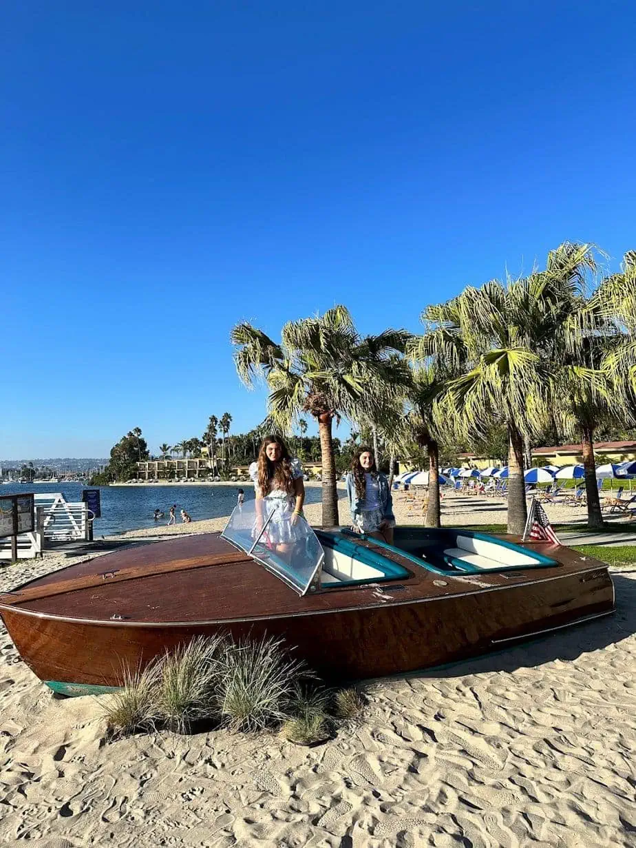 Daughters posing with boat on beach in San Diego