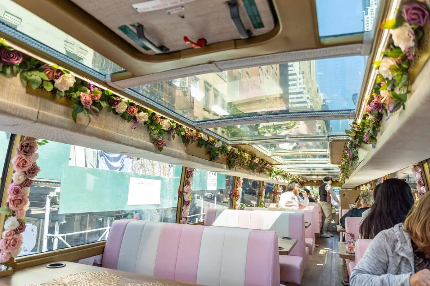 Tea Around Town bus interior adorned with pink and white striped leather seats and ceiling windows surrounded by flowers 