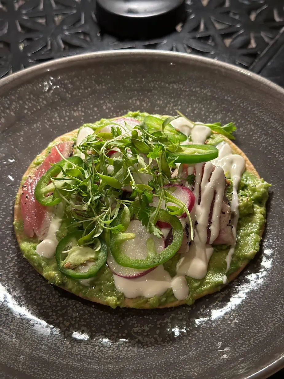 Tostada with avocado onions, micro greens and other vegetables