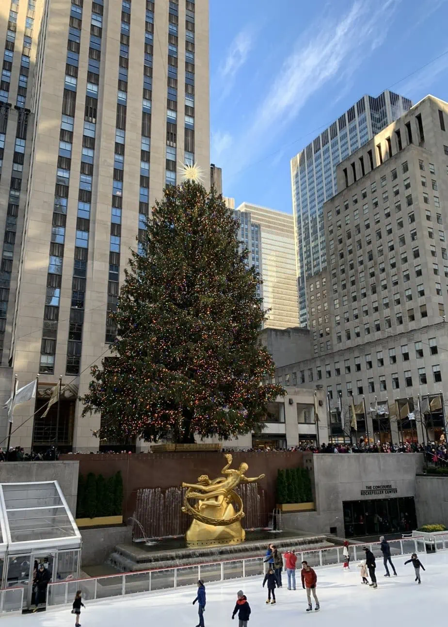 The large Rockefeller Christmas tree looming over the NYC ice skating rink for the perfect NYC Christmas aesthetic 